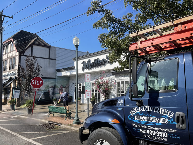 man pressure washing a sidewalk outside a commercial business on Long Island, NY